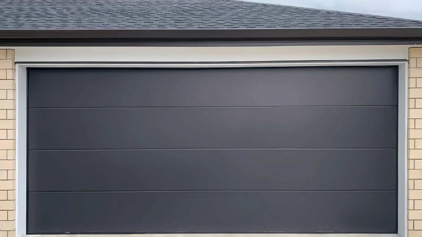 Insulated steel garage door with a panelled leaf on a rendered house front, design rendering