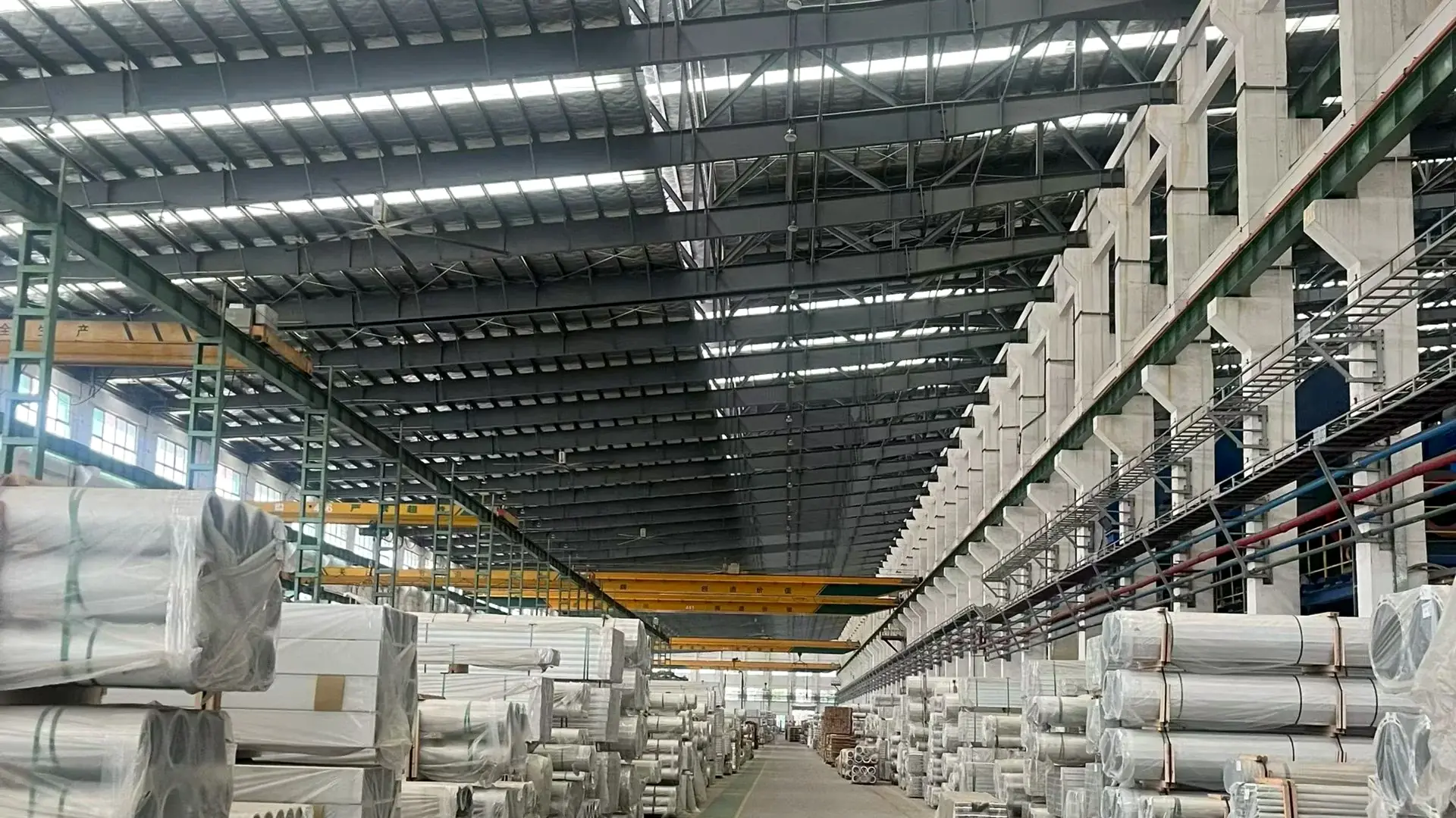 Wrapping and palletising bay in the packing hall, with wrapped profile bundles and overhead gantry crane